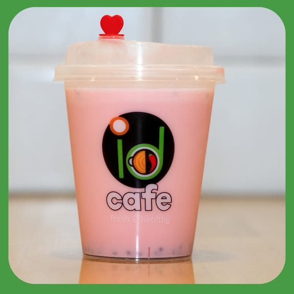 A pink beverage in a clear plastic cup with the ID Cafe logo and a red heart on top.