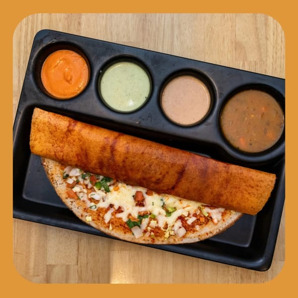 A crispy Indian dosa with cheese and vegetables, served with four different dipping sauces.