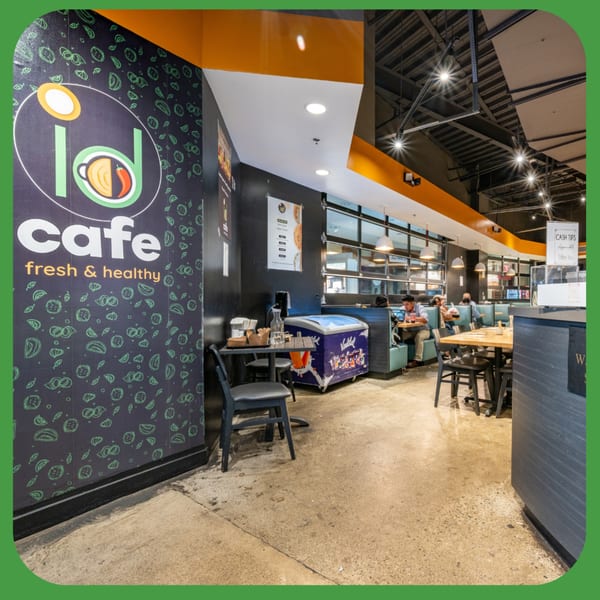Interior of ID Cafe with its logo on a black wall, tables, and customers dining in booths.